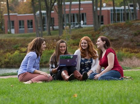 students studying with laptop out in open grassy area